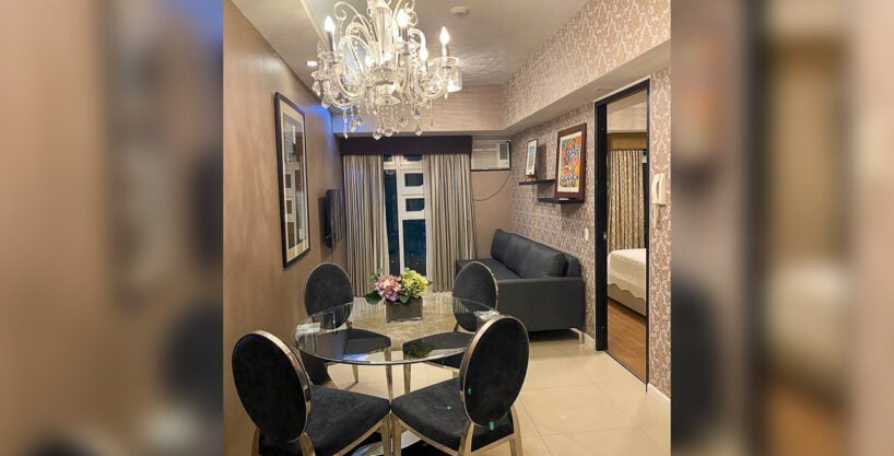 Dining area with crystal chandelier and velvet chairs in a furnished 1BR condo at Solinea Tower 1