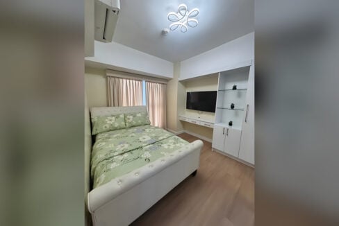 Main bedroom with a wall-mounted TV, built-in storage and split-type aircon