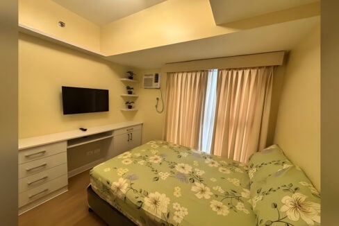 Second bedroom with a built-in desk and drawers, wall-mounted TV and floating shelves