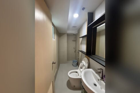 Bathroom with a tiled shower area, wall-hung basin and mirror shelf