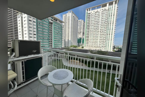 Balcony with a rattan bistro set overlooking the landscaped lawns of Solinea
