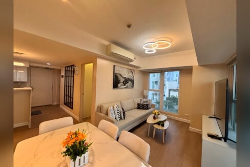 Living room seen from the dining table, with the entry and a black-grid mirror panel beyond