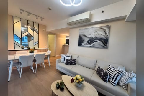 Sofa and abstract artwork beside the dining area with a geometric mirrored wall