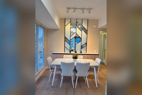 Dining area under track lighting with a geometric mirrored wall