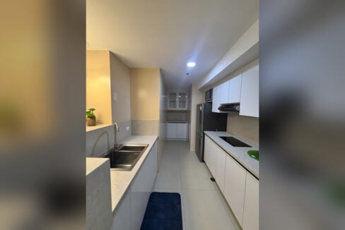 White galley kitchen with an induction hob, range hood, built-in microwave and refrigerator