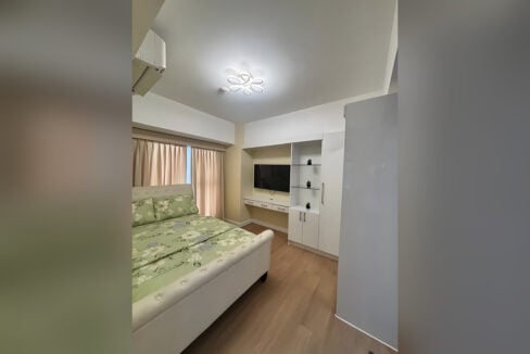 Main bedroom with a tufted sleigh bed, built-in desk and glass display shelves
