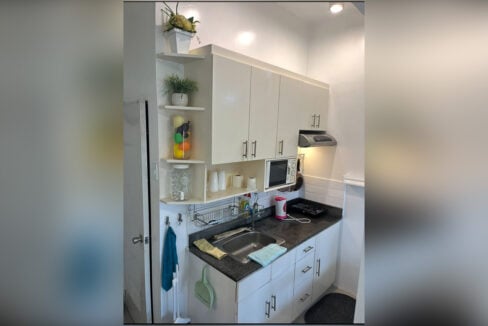 White kitchenette cabinets with corner shelves and a granite countertop
