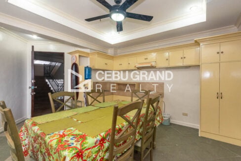 Dining area with a six-seater table beside the kitchen cabinets at Trinity Plaza