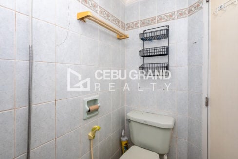 Toilet with bidet spray and a wall-mounted wire shelf