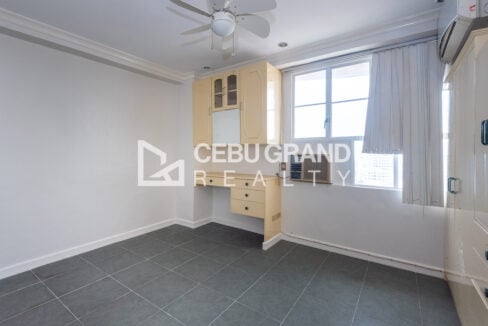 Master bedroom with a built-in study desk and cabinets by the window at Trinity Plaza