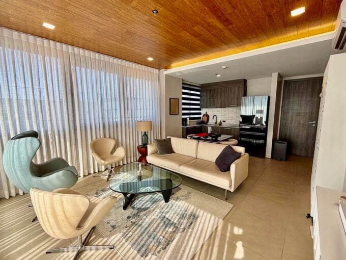 Living area with egg and swan chairs, cream sofa and wood-plank ceiling in a 2BR corner condo for sale at The Reef, Mactan
