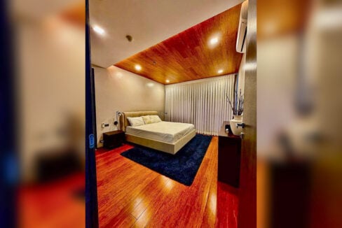 Master bedroom with bamboo flooring, wood ceiling and navy rug in a 2BR corner condo for sale at The Reef, Mactan