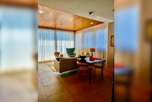 Living area with sheer curtains, lounge chairs and dining table in a 2BR corner condo for sale at The Reef, Mactan