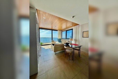 Corner living area with floor-to-ceiling windows facing the sea in a 2BR corner condo for sale at The Reef, Mactan
