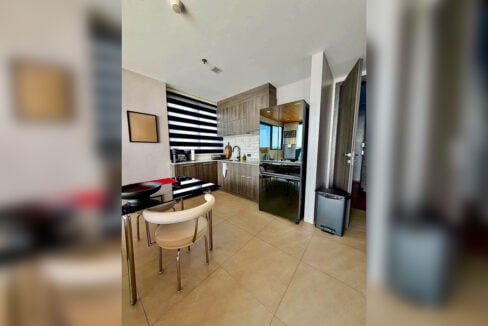 Kitchen with dark wood-grain cabinets and black French-door refrigerator in a 2BR corner condo for sale at The Reef, Mactan