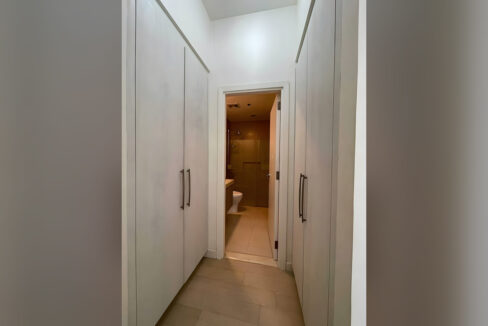 Walk-through closet lined with built-in wardrobes leading to the bathroom